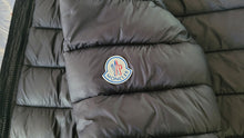 Cargar imagen en el visor de la galería, Gray puffer jacket with Moncler logo on a neutral background